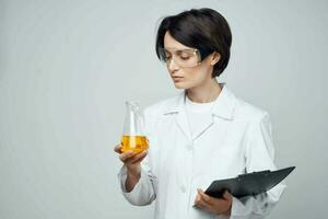 fêmea laboratório assistente dentro uma branco casaco teste tubo com uma químico solução análise foto