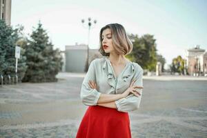 alegre mulher dentro vermelho saia dentro a quadrado ao ar livre posando foto