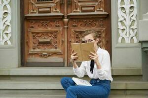 curto cabelos mulher com uma livro dentro dele mãos ao ar livre lendo estilo de vida foto