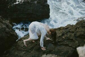 mulher sobe rochoso pedras de a oceano viagem foto