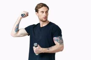 homem dentro Preto camiseta com tatuagem em dele braço e halteres músculo fisiculturista foto