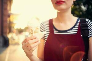 alegre mulher em a rua comendo gelo creme andar verão foto