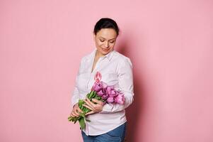 encantador mulher com Rosa cetim fita, segurando ramalhete do tulipas. Outubro Rosa mês. seio Câncer consciência campanha foto