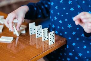 Garoto jogando com dominó, fechar acima. Construir uma dominó cerca, fechar acima foto