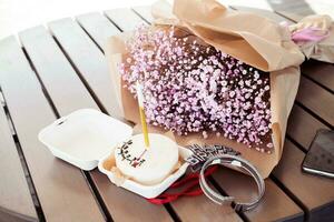 bento bolo com uma vela com uma ramalhete do Rosa Gypsophila em uma de madeira mesa, dentro uma cafeteria. pequeno surpresa para uma garotas aniversário foto