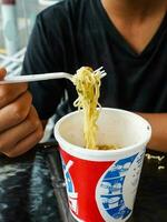 instante Macarrão, macarrão sopa dentro uma xícara, Rapazes mão alimentando pronto para comer Macarrão foto