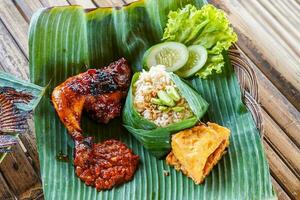 grelhado frango com vermelho churrasco molho, legumes e Pimenta molho servido em banana folhas foto