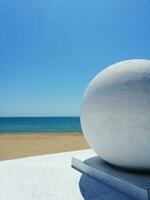 arquitetônico elemento - uma branco bola em a fundo do a mar, areia e céu foto