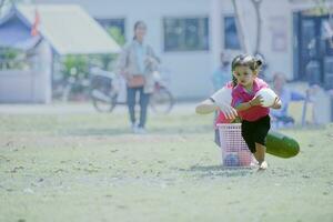 menina segurando uma branco bola dentro dela mãos, corrida dentro a parque, jogando com dela crianças amigos. foto