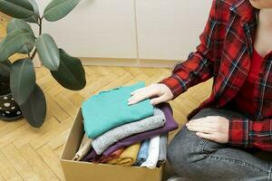 mulher pacotes roupas dentro caixas para doando. foto