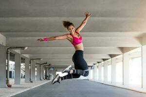 ginástica mulher pulando ao ar livre dentro urbano ambiente. ativo mulher ser cheio do energia, saltos Alto dentro ar, prepara para esporte competições. . ginástica conceito foto