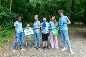 diverso grupo do pessoas colheita acima Lixo dentro a parque voluntário comunidade serviço. feliz internacional voluntários segurando cartaz com 'salvar a terra' mensagem. foto