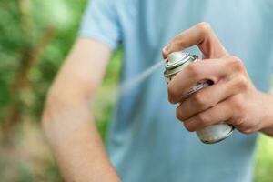 homem aplicando inseto repelente contra mosquito e Carraça em dele braços durante caminhar dentro natureza. pele proteção contra inseto mordida foto