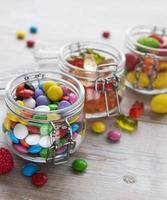 doces coloridos em potes na mesa foto