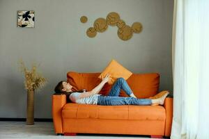 sorridente mulher relaxante às casa dentro a quarto em a sofá interior apartamentos foto
