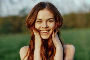 retrato do uma jovem ruiva mulher olhando para dentro a Câmera e sorridente, fechar-se retrato do uma rindo mulher dentro a configuração luz solar foto