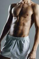 desportivo masculino fisiculturista com abdômen cubos em estômago cinzento fundo foto