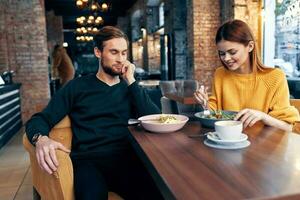 alegre jovem casal sentado dentro uma restaurante descansar comendo foto