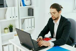 homem de negocios trabalhos dentro a escritório dentro frente do uma computador portátil estilo de vida foto