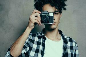 bonito cara com uma Câmera perto dele face e encaracolado cabelo xadrez camisa passatempo fotógrafo foto