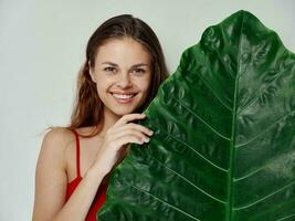 alegre mulher dentro uma vermelho roupa de banho verde folha exótico luz fundo foto