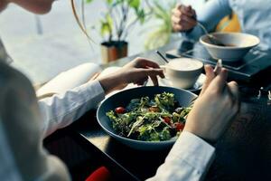 fresco salada dentro uma prato delicioso Comida dieta garfo dentro mão fêmea mãos cafeteria foto