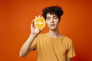 alegre encaracolado cara com laranjas dentro dele mãos frutas estilo de vida foto