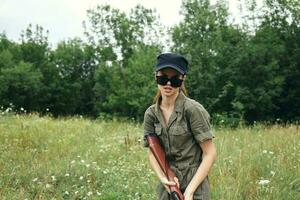 mulher em ao ar livre oculos de sol com fresco ar arma de fogo verde folhas verde foto