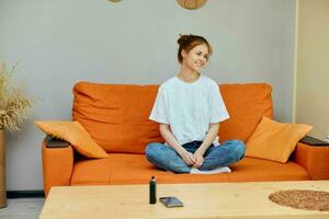 mulher às casa em laranja sofá telefone em mesa e vape foto