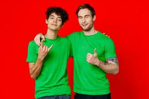 dois homens abraçando dentro verde Camisetas em uma vermelho fundo foto