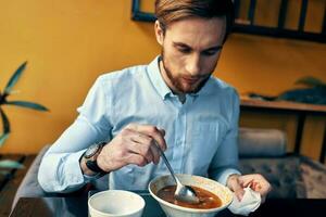 homem comendo borscht e Arroz a grega cafeteria restaurante interior o negócio finança camisa modelo foto