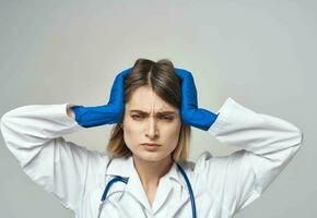 emocional mulher dentro azul médico luvas toques dela cabeça com dela mãos foto