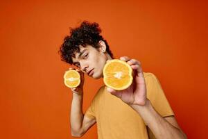 bonito homem com encaracolado cabelo laranjas dentro mãos estúdio isolado fundo foto