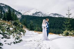 noivo em um terno azul e noiva em branco nas montanhas dos Cárpatos foto