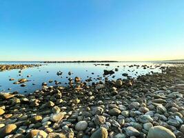 rochoso de praia com calma mar e azul céu foto