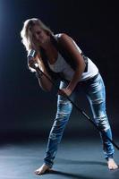 jovem loira com roupas jeans em um fundo escuro foto