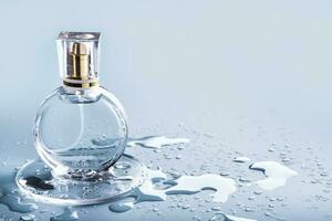 vidro perfume garrafa e gotas água em azul fundo. inverno ou Primavera fragrância foto