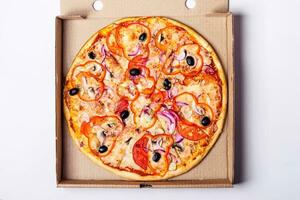 vegetariano pizza com tomate, doce Pimenta e azeitonas dentro embalagem caixa em cinzento fundo foto