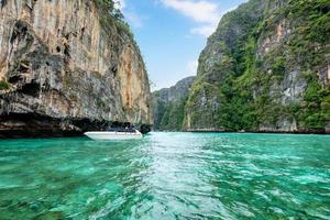 barco a motor navegando na lagoa de pilha de calcário na ilha de phi phi foto