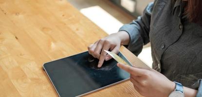 mão de uma mulher segurando o cartão de crédito com o uso do laptop para fazer compras online ao fazer pedidos em casa. conceito de negócios, estilo de vida, tecnologia, comércio eletrônico, banco digital e pagamento online. foto