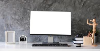 área de trabalho do designer criativo com tela de laptop em branco e pôster de maquete na mesa branca foto