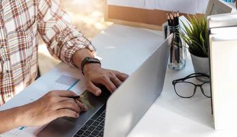 close-up do empresário ou contador mão segurando caneta trabalhando no computador laptop para calcular dados de negócios, documento de contabilidade e calculadora no escritório, conceito de negócio foto