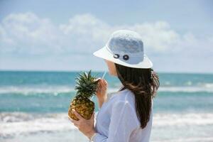 mulher tendo uma tropical beber às uma paradisíaco tropical de praia dentro uma lindo ensolarado dia foto