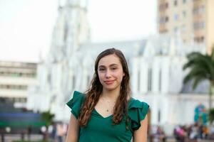 lindo turista menina às a ortiz ponte com la ermita Igreja em fundo dentro a cidade do cali dentro Colômbia foto