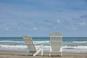 esvaziar branco de madeira cadeiras às uma paradisíaco de praia em a trópicos dentro uma lindo ensolarado dia foto