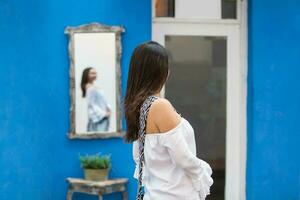 lindo mulher em branco vestir olhando às ela mesma em uma espelho em a colorida ruas do a colonial murado cidade do cartagena de índias foto