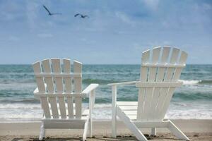 esvaziar branco de madeira cadeiras às uma paradisíaco de praia em a trópicos dentro uma lindo ensolarado dia foto