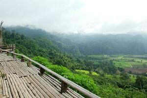 de madeira terraço para ponto de vista em a vale phu lang kha montanha e lindo vegetação floresta dentro chuvoso estação do Tailândia foto