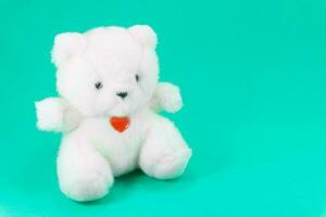 adorável branco Urso de pelúcia Urso brinquedo sentado com vermelho coração em verde fundo, outono dentro amor Urso de pelúcia urso, brinquedo para crianças foto