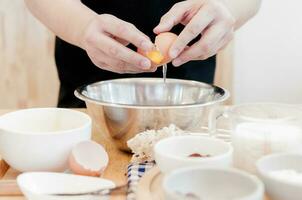 homem dentro a cozinha cozinhando uma massa. mãos rompe a ovo para dentro uma tigela ,mãos derramando mordido ovo ,cozimento conceito foto
